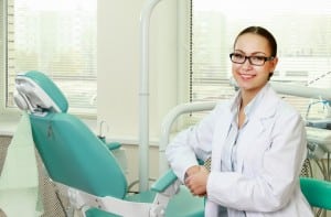 female dentist posing next to dental chair