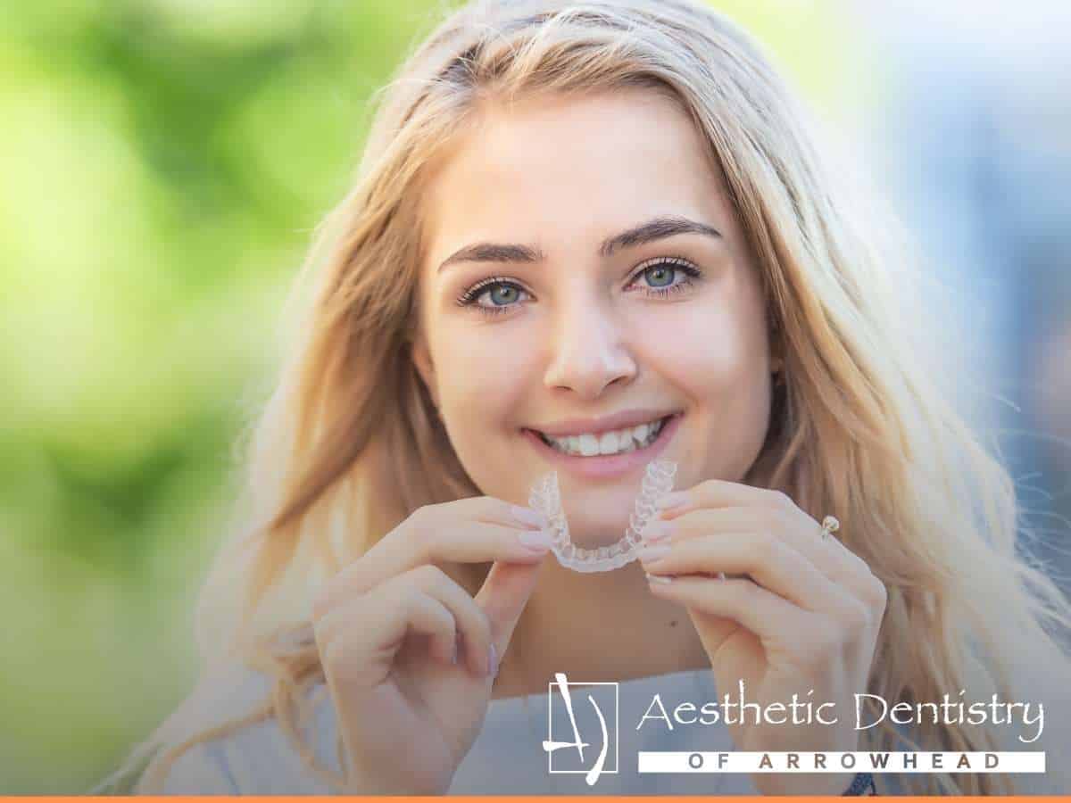 Young woman holding a clear removable retainer